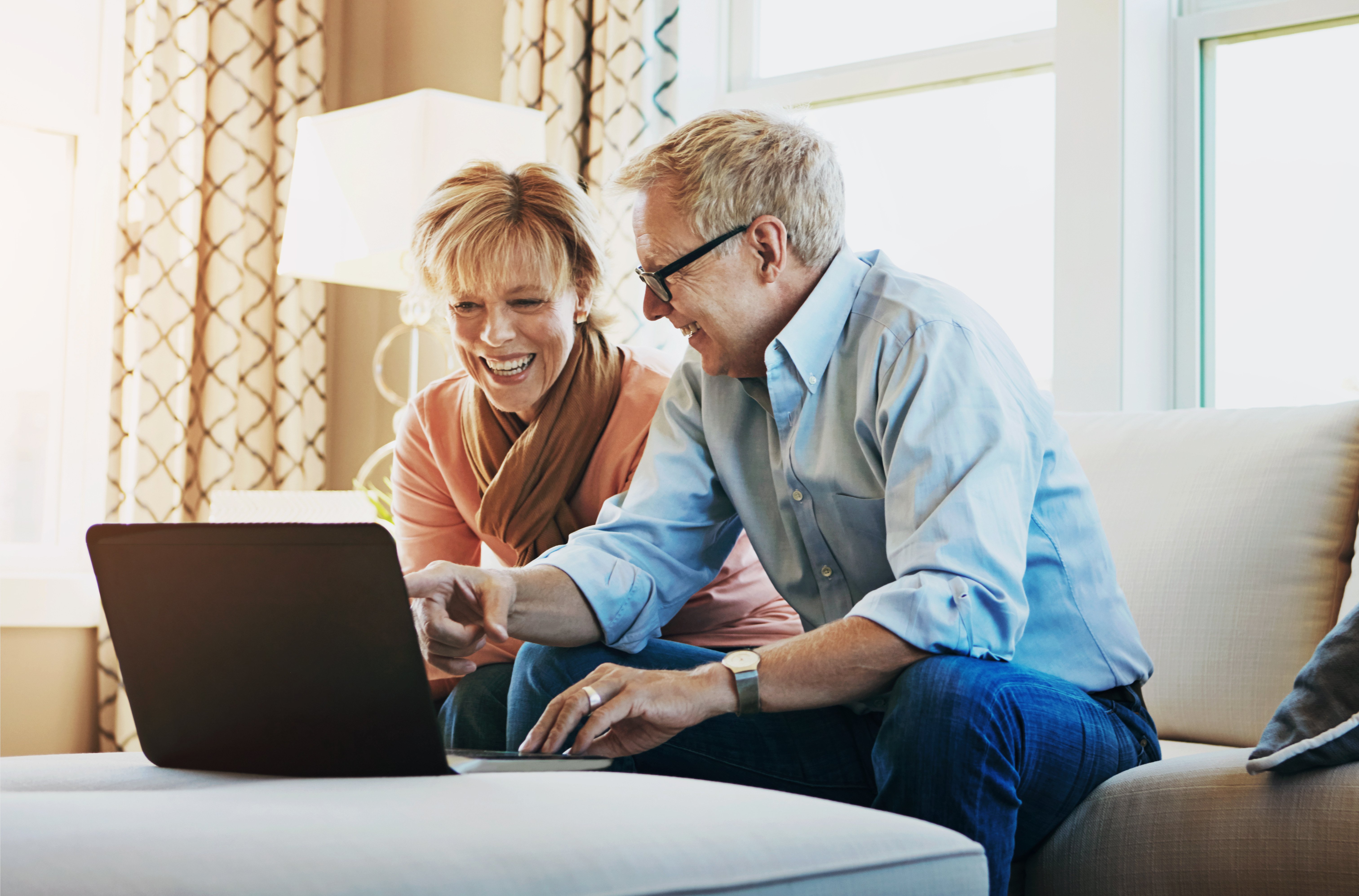 A couple work together on a laptop, planning to pay off their home sooner by refinancing over a shorter term.