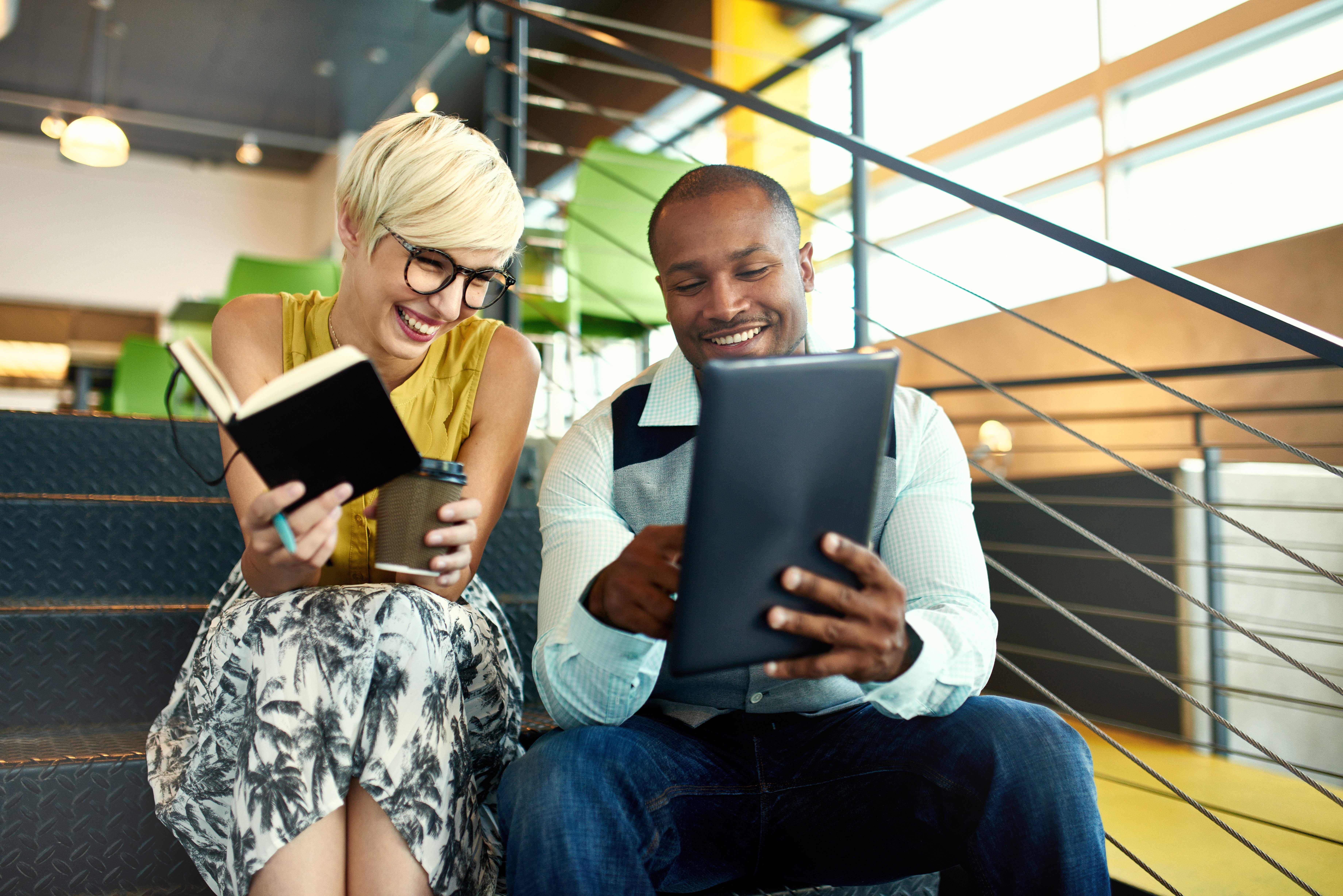 Two business owners smile while analyzing how much their business savings have grown in their business CD account.