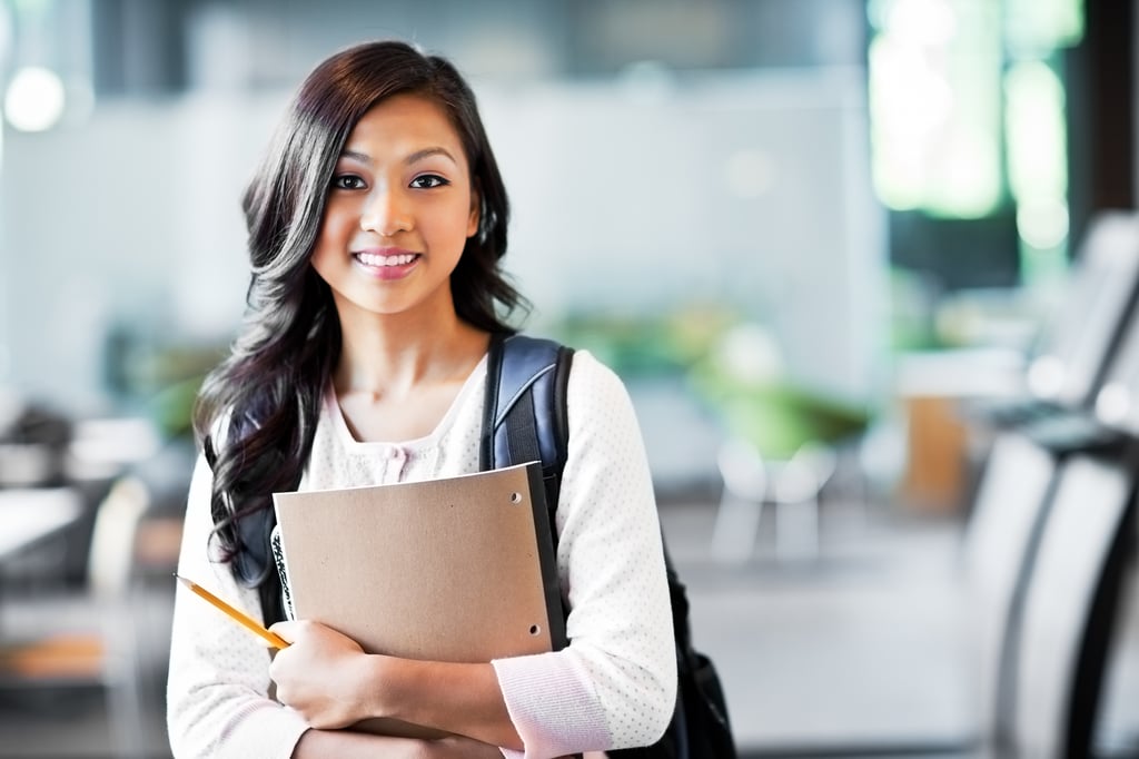 A female student is holding the books she bought using the funds of her Coverdell Education Savings Account.