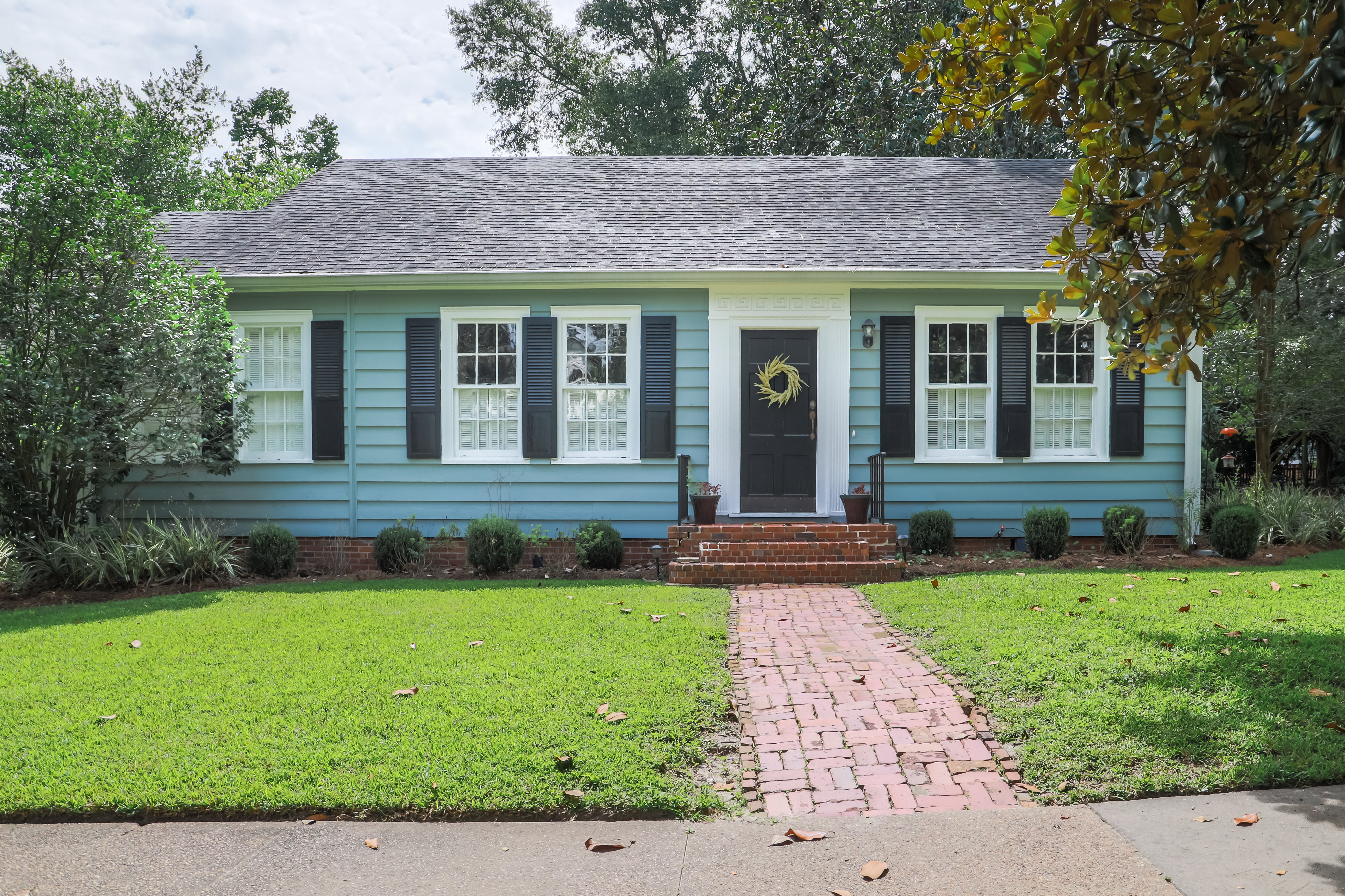 A recently renovated small blue cottage in a rural area.