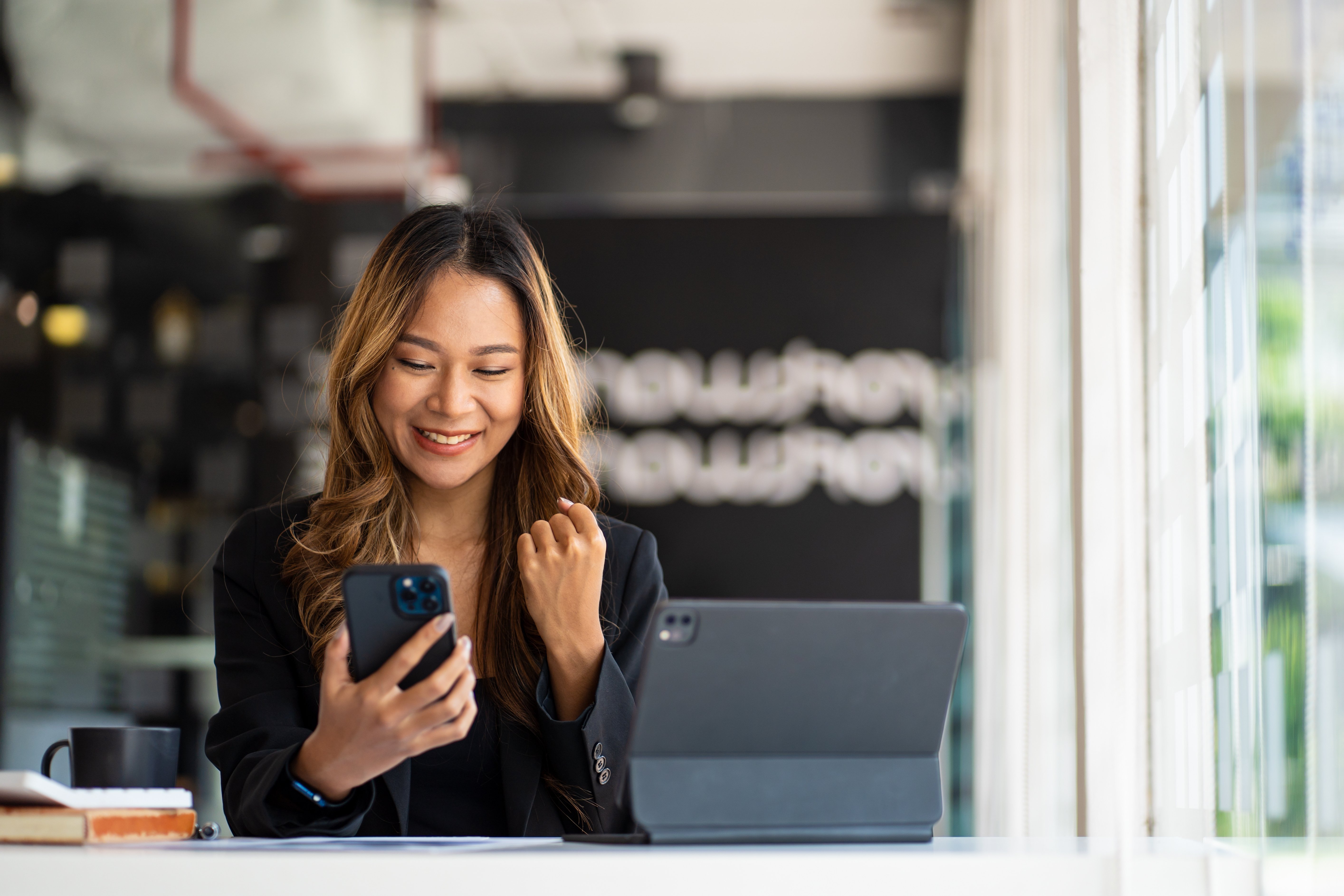 A business owner celebrates as she checks her mobile banking app to see how much she’s earned with our competitive business savings rates.