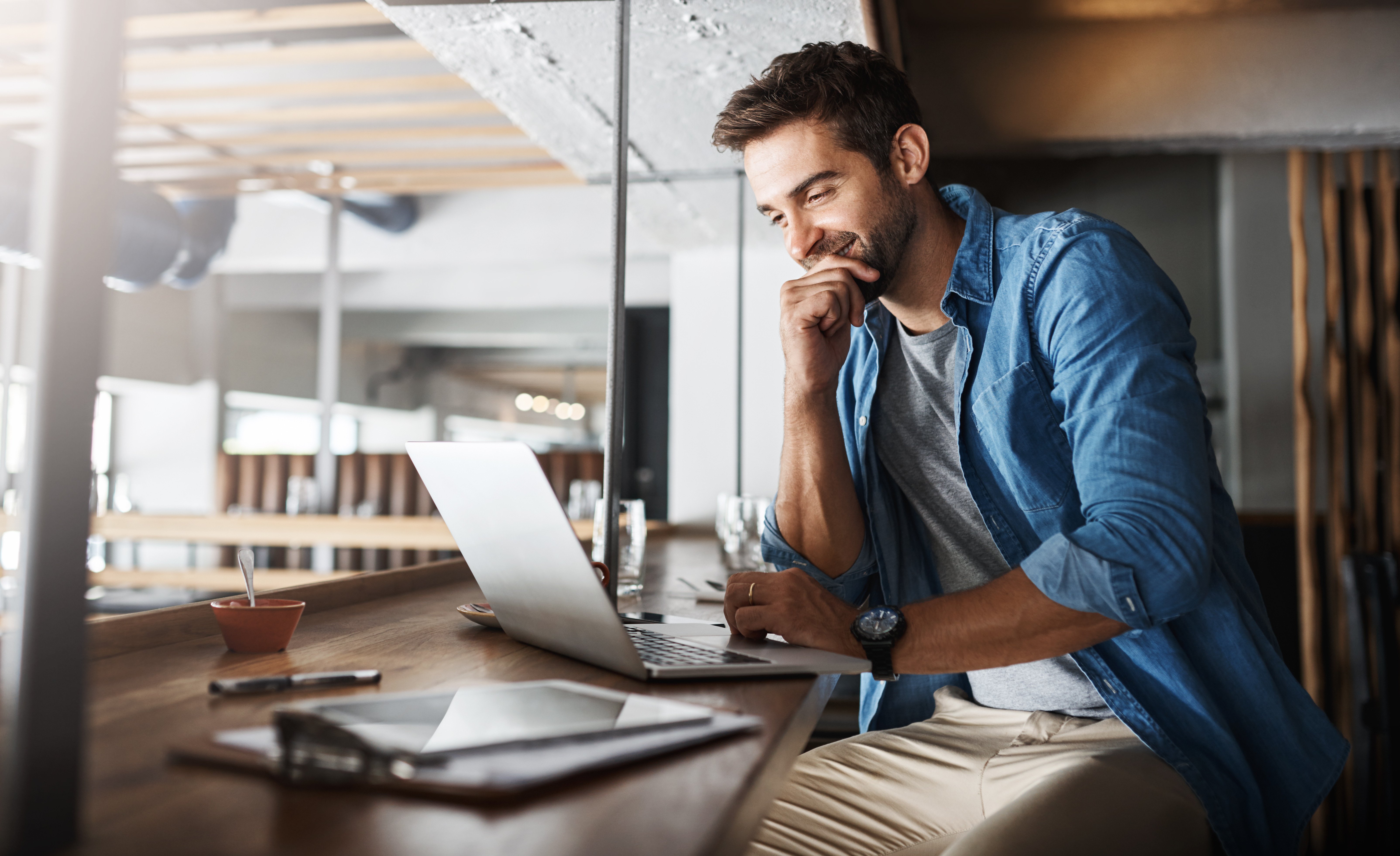 A young man reading the benefits of a Business Money Market Account on his laptop.