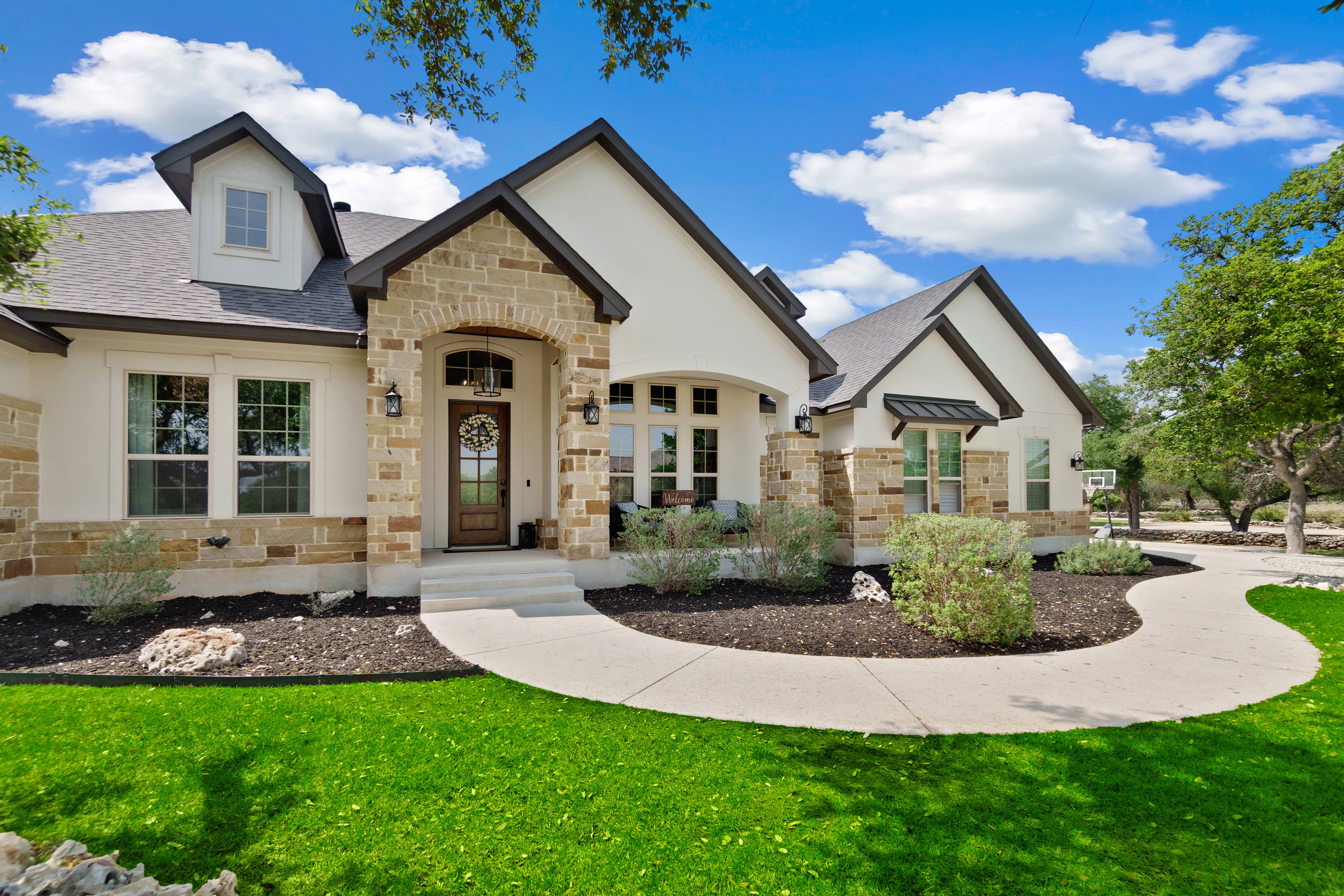Front view of a white home with stone trim set in a green lawn.