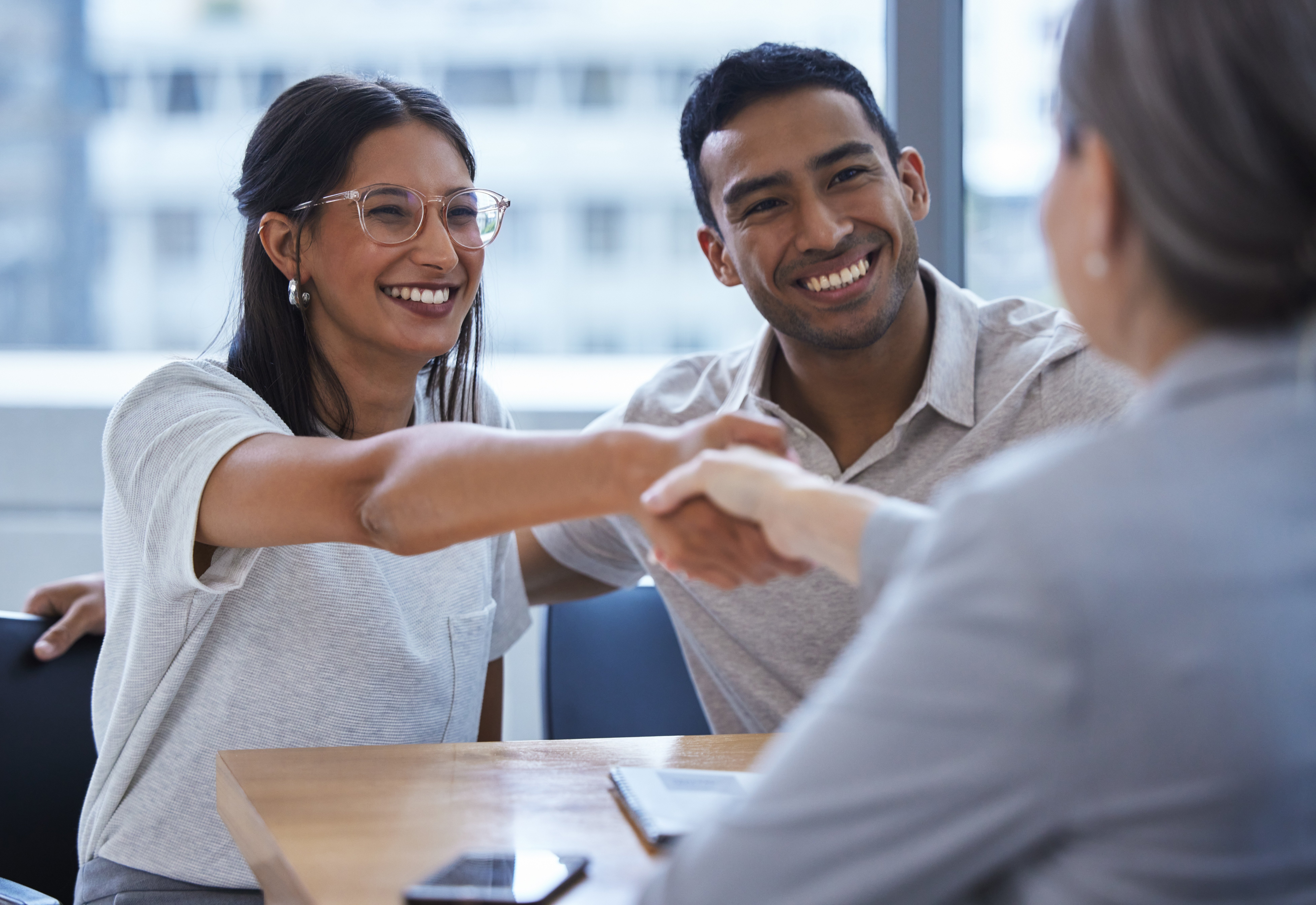AdobeStock_6A couple shake hands with a credit union loan officer.27348001