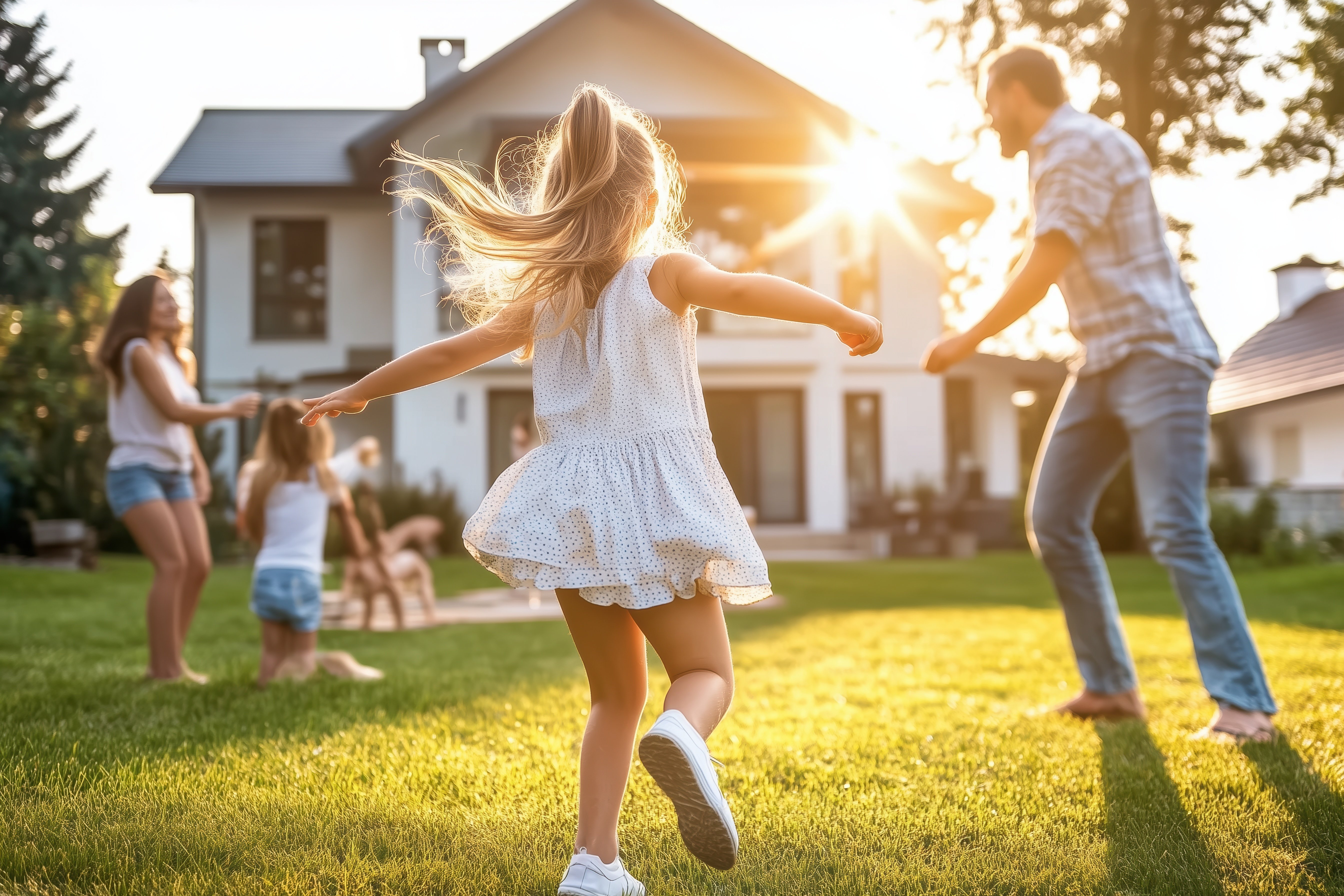 A young family of four plays together in the back yard of their large home.