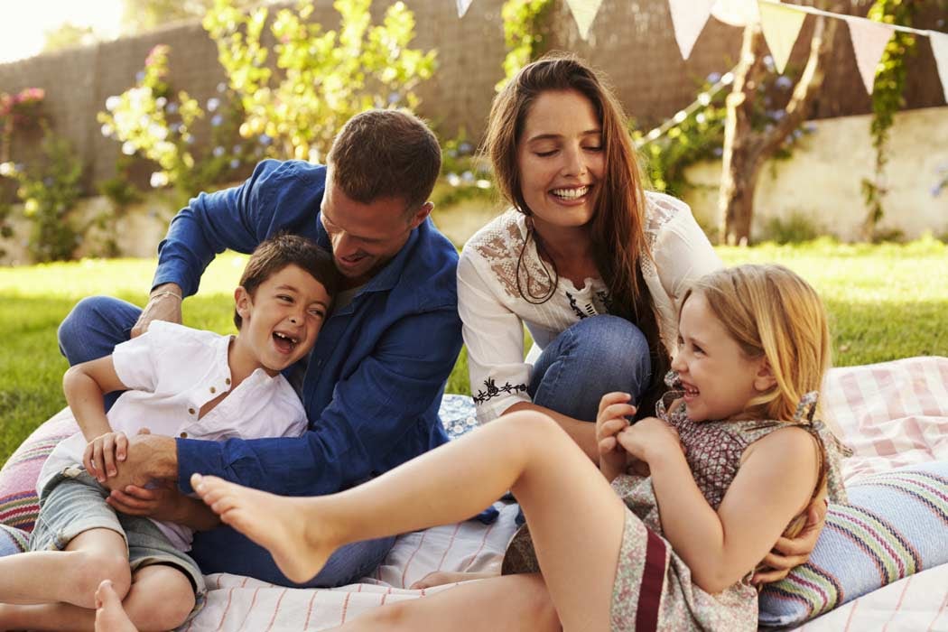 Family laughing and sitting on blanket in yard