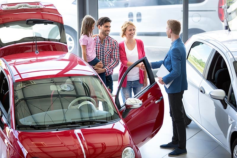 Family looking at cars with salesman at dealership