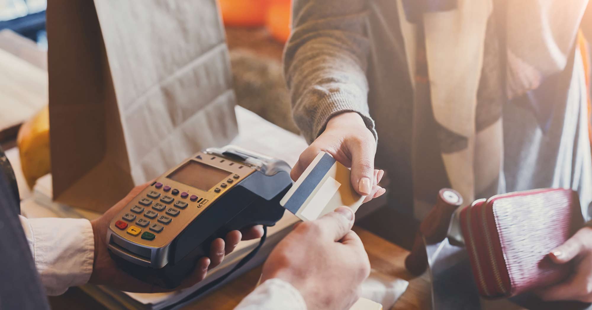 Person handing credit card to cashier holding machine