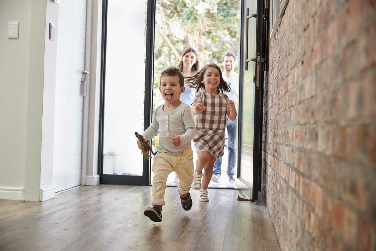 Family running in open front door to house