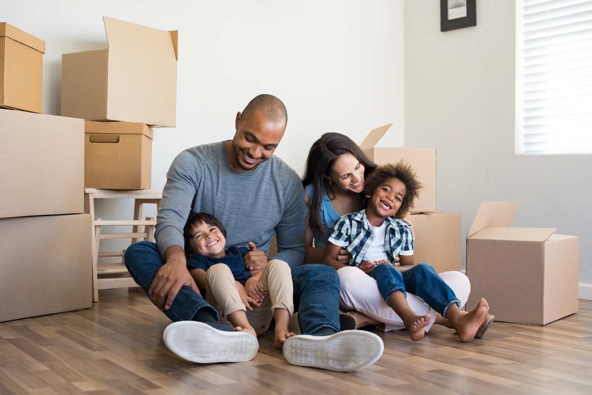 Parents and kids sitting together surrounded by moving boxes