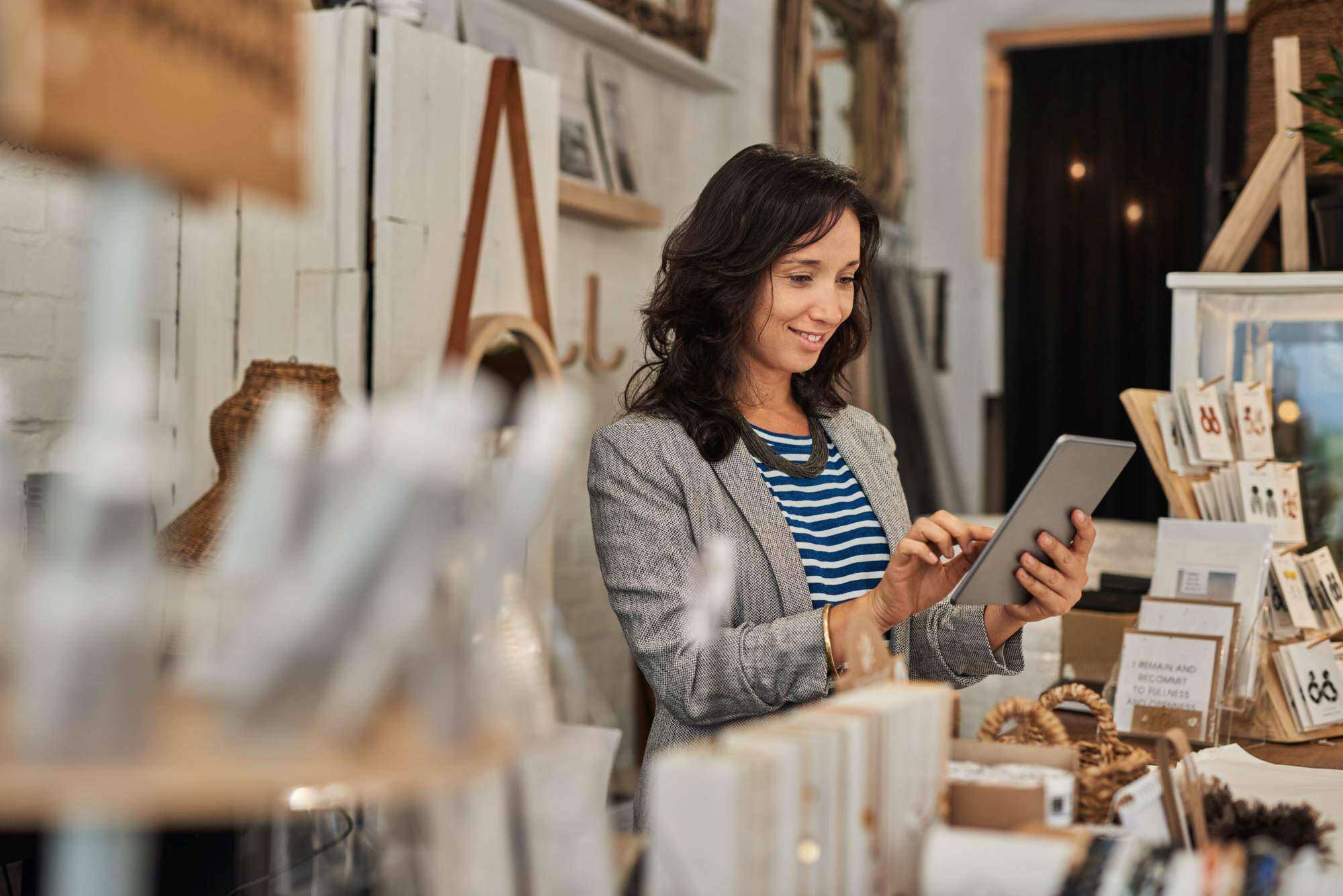 A woman happily managing her business finances online with Pinnacle Business Checking on her tablet.