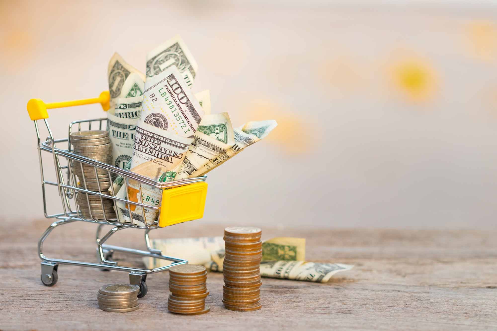 Cash and coin in a miniature shopping cart
