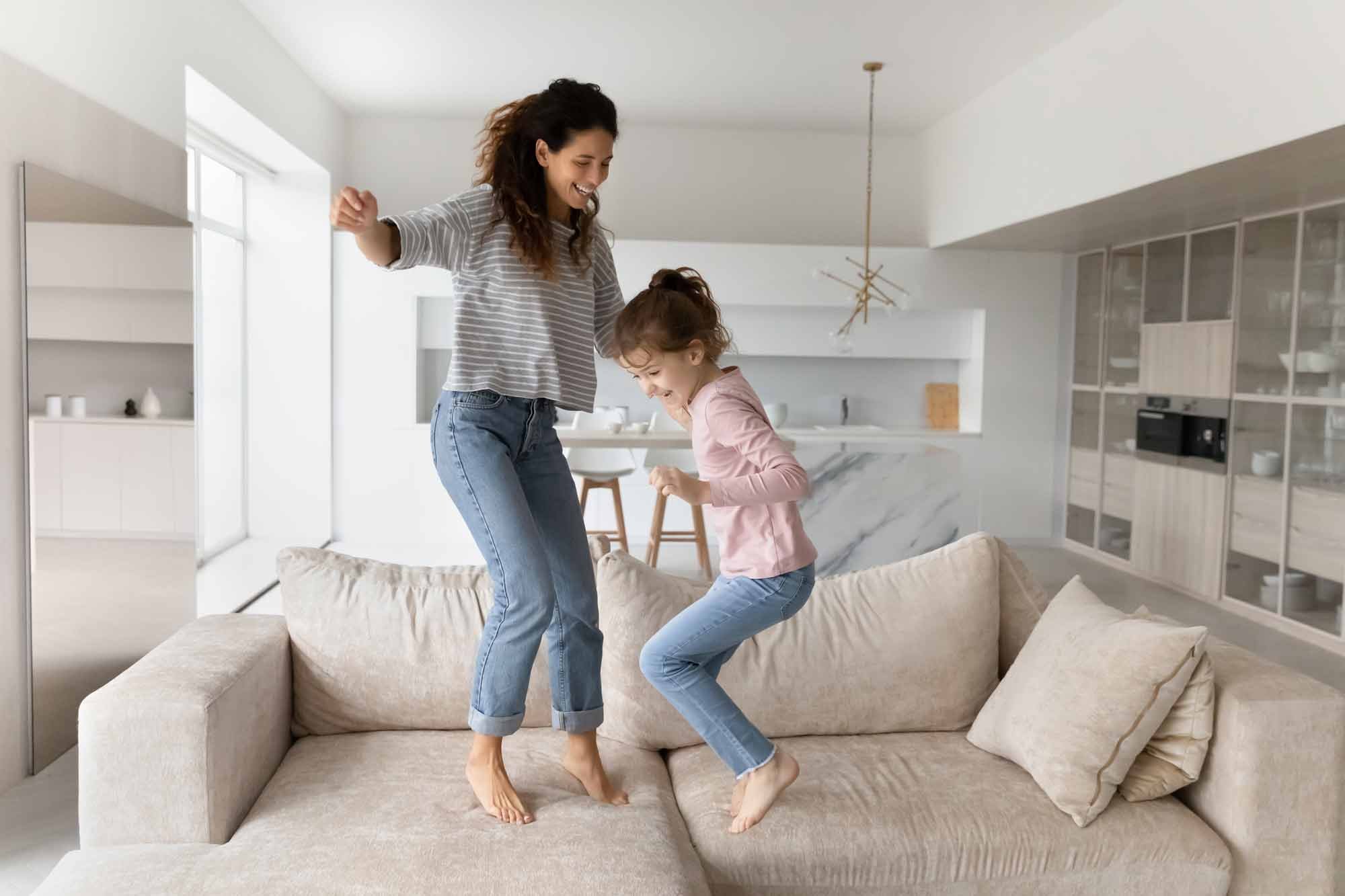 Mom and daughter jumping on the couch