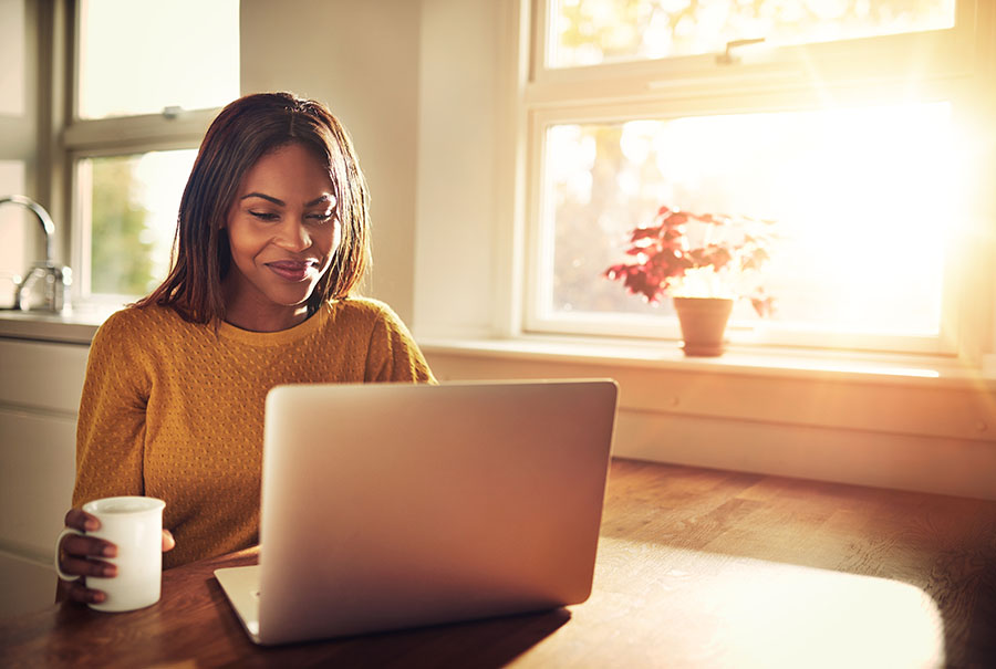 a woman reads a financial blog as she drinks her morning coffee.