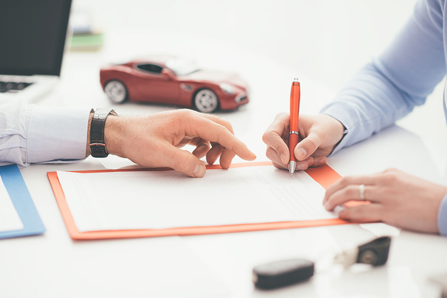 A person is signing an auto loan contract.