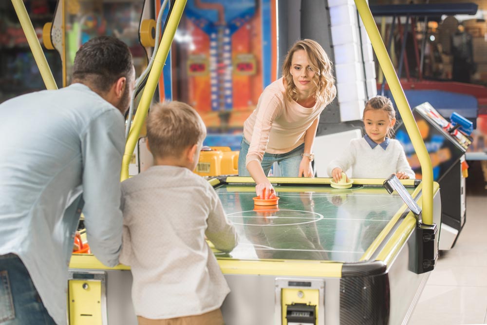Family playing air hockey together for budget entertainment
