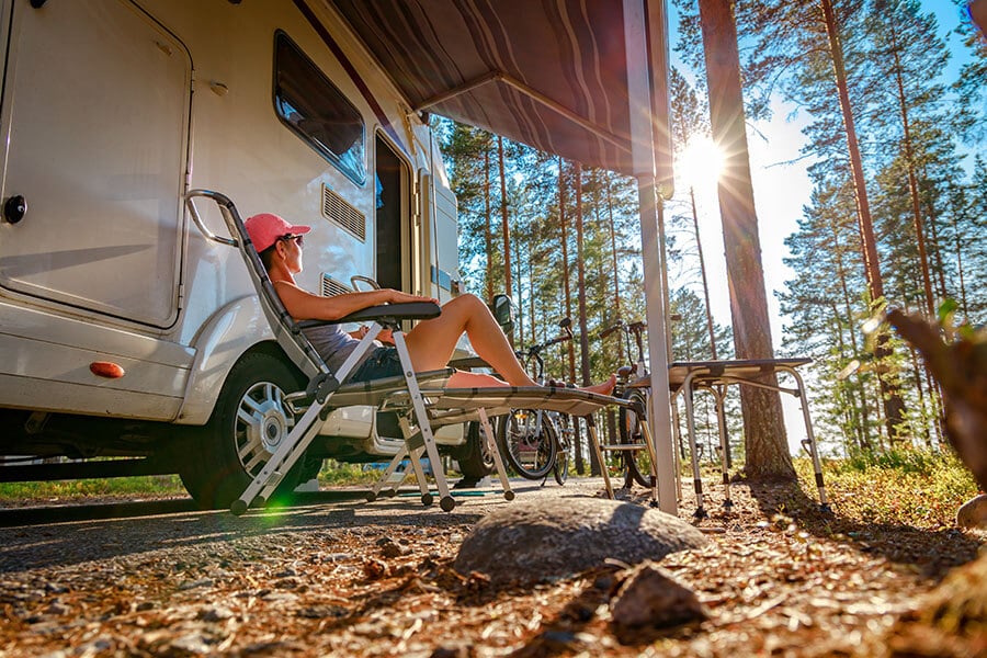A woman sitting in the sunshine outside the RV she bought with an RV loan.
