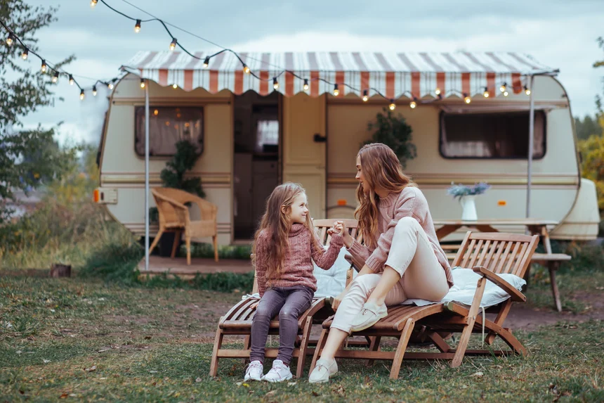 After learning how to finance an RV, a mother sits with her daughter in front of the camper she bought with an RV loan.