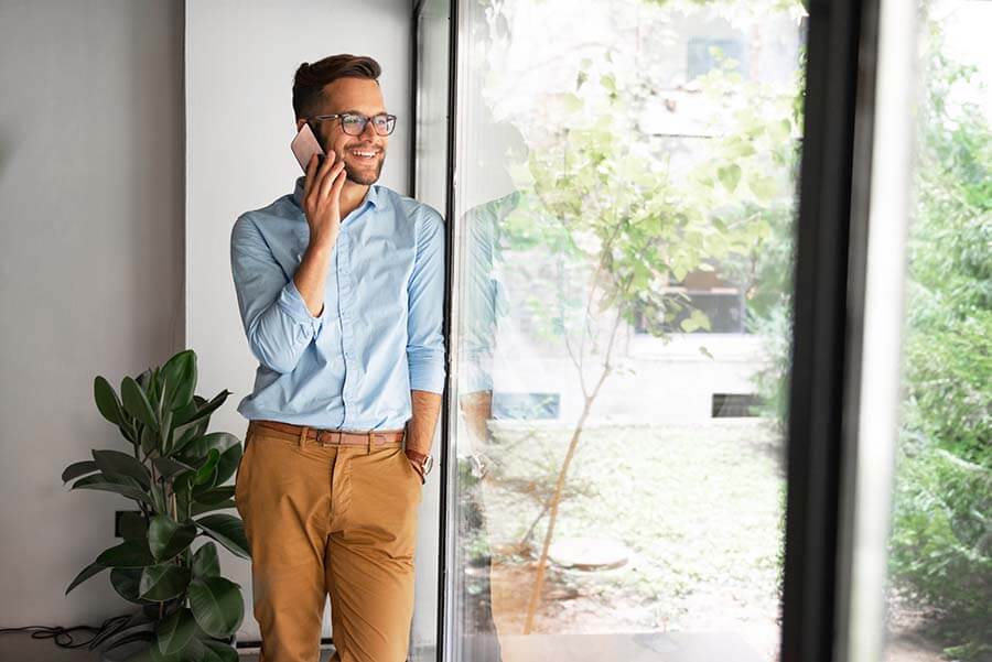 A young man is happy to make his loan payment over the phone.