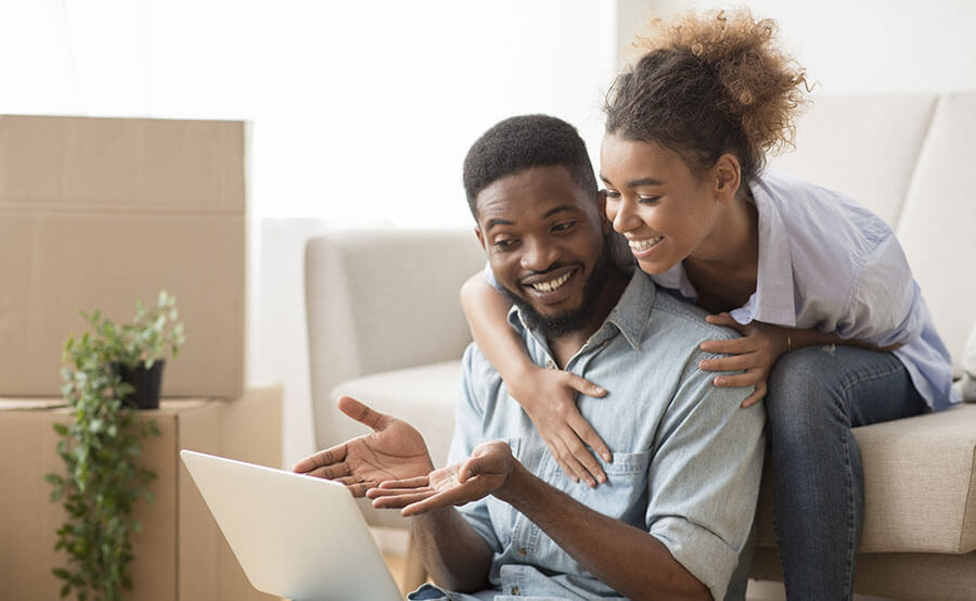 A happy husband and wife look at a laptop to determine how to use their funds during the HELOC draw period.