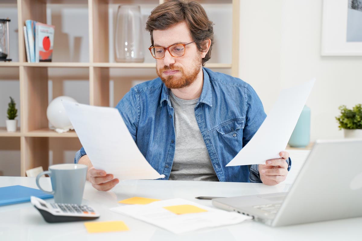 Man looking upset about paperwork for car loan with poor credit