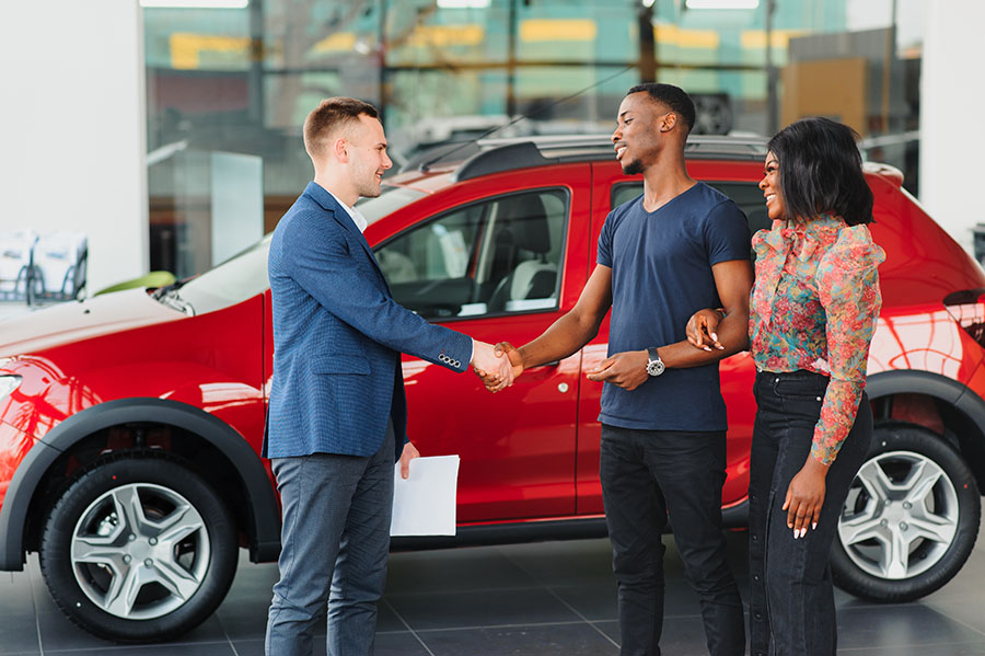 A happy couple is at the dealership buying a car with a credit union auto loan.
