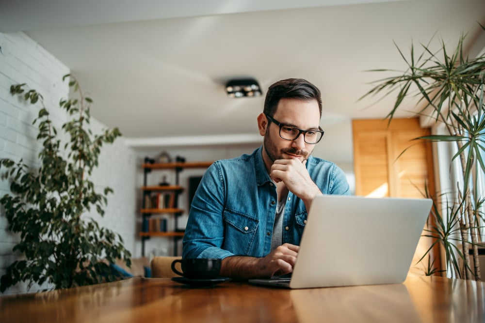 A man does research on his laptop about the benefits of a money market account.