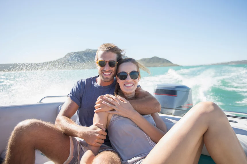 An attractive couple sitting on the back of a power boat they bought with boat financing.