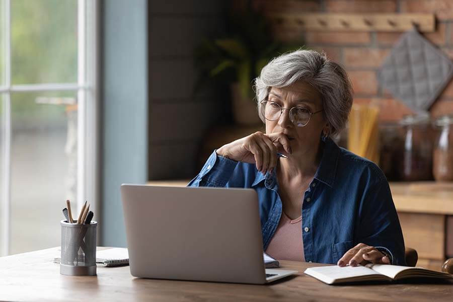 A thoughtful middle aged woman does online research about the differences between a SIMPLE IRA vs. a traditional IRA.