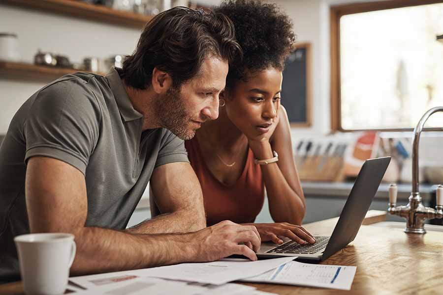 A couple in their kitchen on a laptop doing research about the difference between a home equity loan and a mortgage.