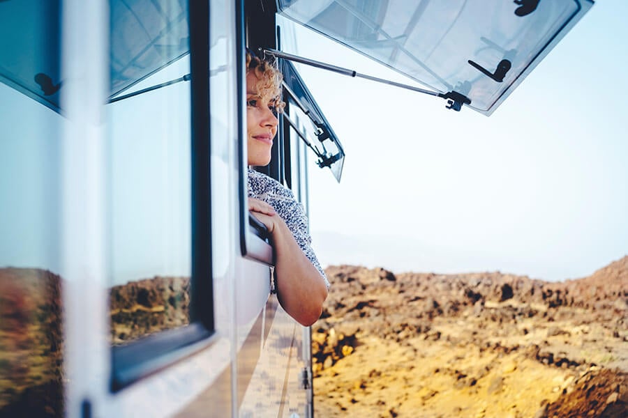 A woman gazes out of the window of her RV, which she bought with zero down RV financing.