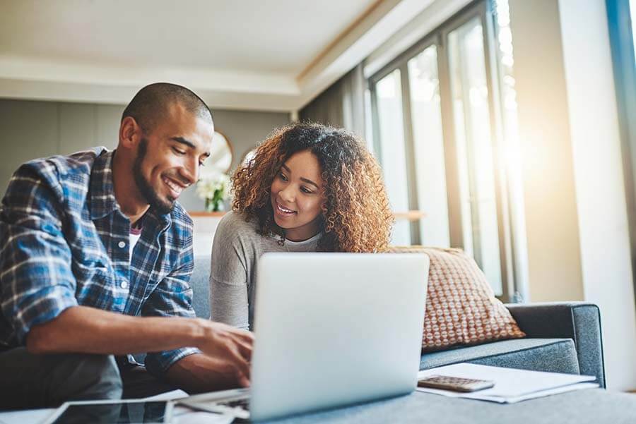 A young couple at a laptop doing research to see if certificates of deposit are worth it.