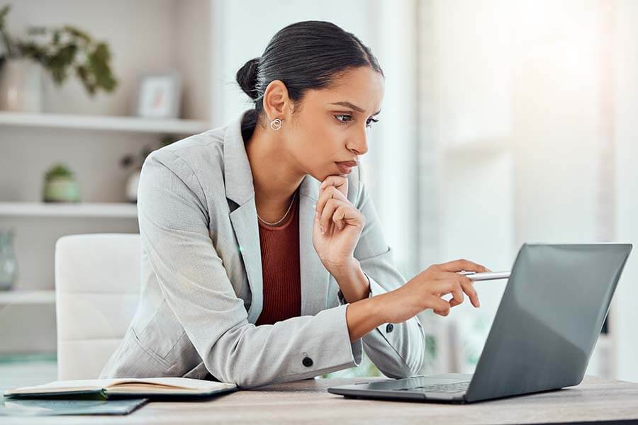 A young professional woman does research on her laptop about the differences between a money market and a CD.