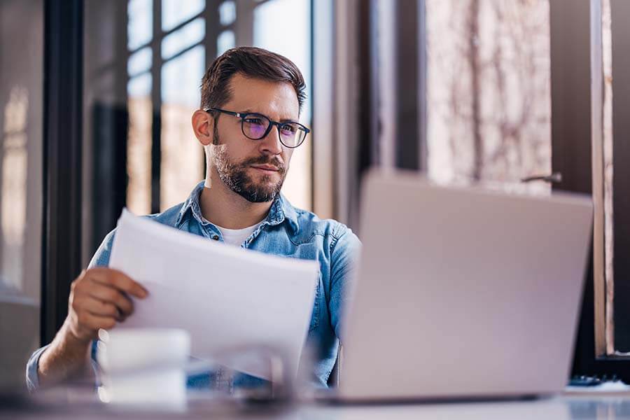 A younger man researching how a money market account works on his laptop.