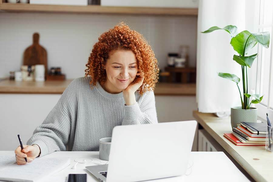 A woman is looking at her laptop and using Online Banking and Bill Pay to make her loan payment.