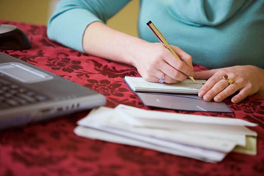 A young woman is writing a check for her loan payment.