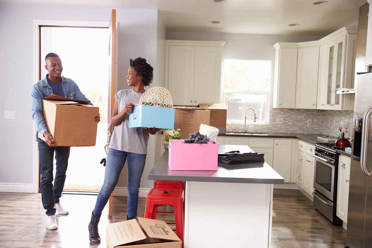 Couple walking into new house with boxes