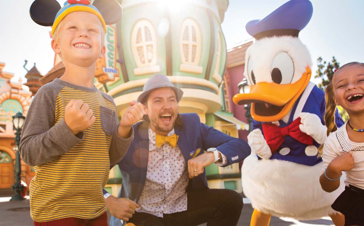 Happy boy standing by Donald at Disneyland