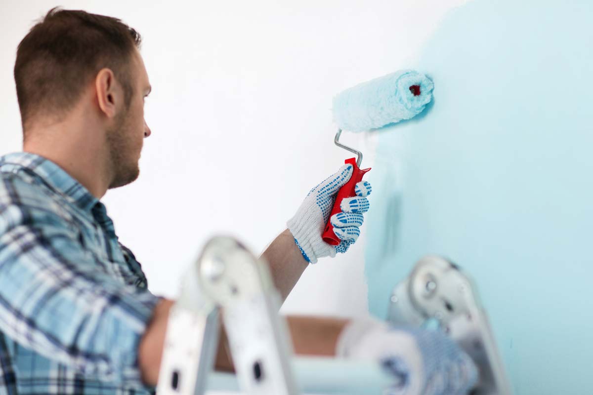 man rolling paint onto wall