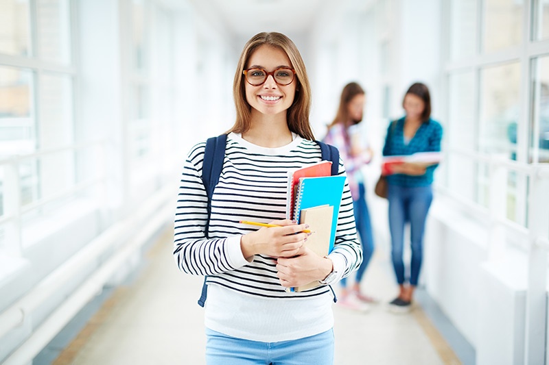 Female college student holding books in hallway