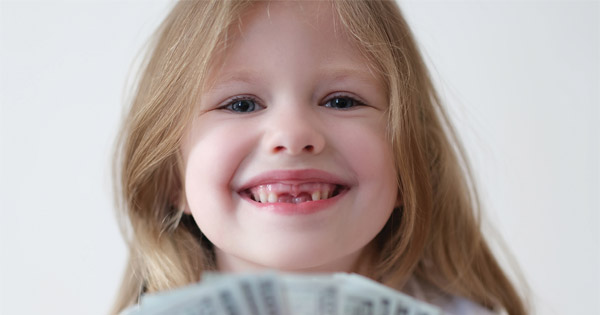 young girl smiling with missing teeth. she is holding out a fan of cash