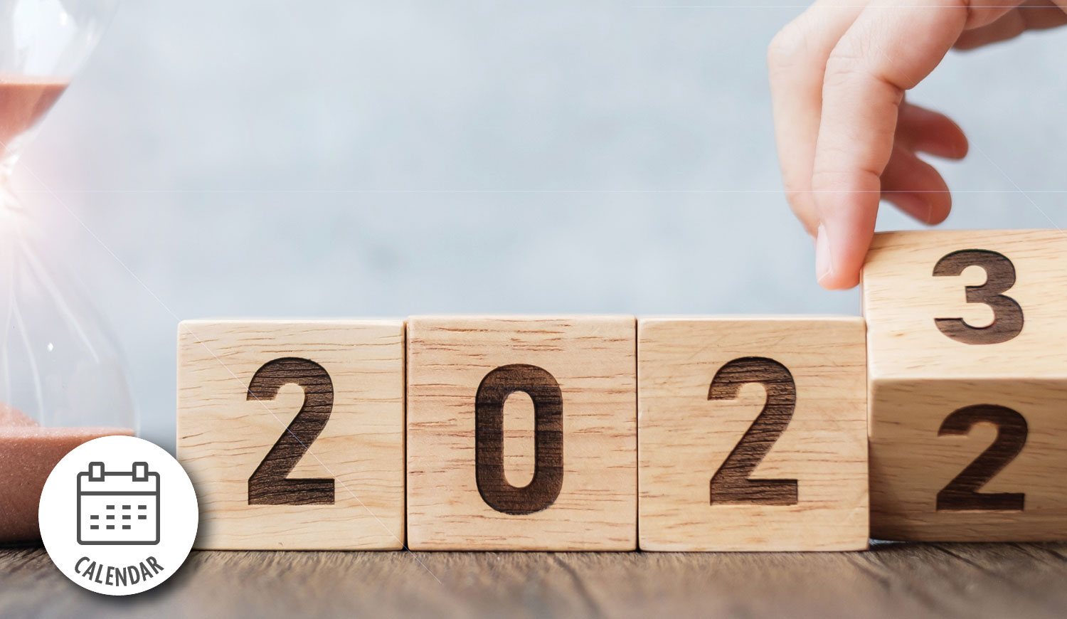 wooden blocks with numbers spelling out the year. a hand is turning the last block so 