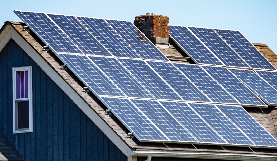 solar panels on the roof of a house with chimney showing against blue sky