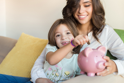 Little girl putting money in piggy bank