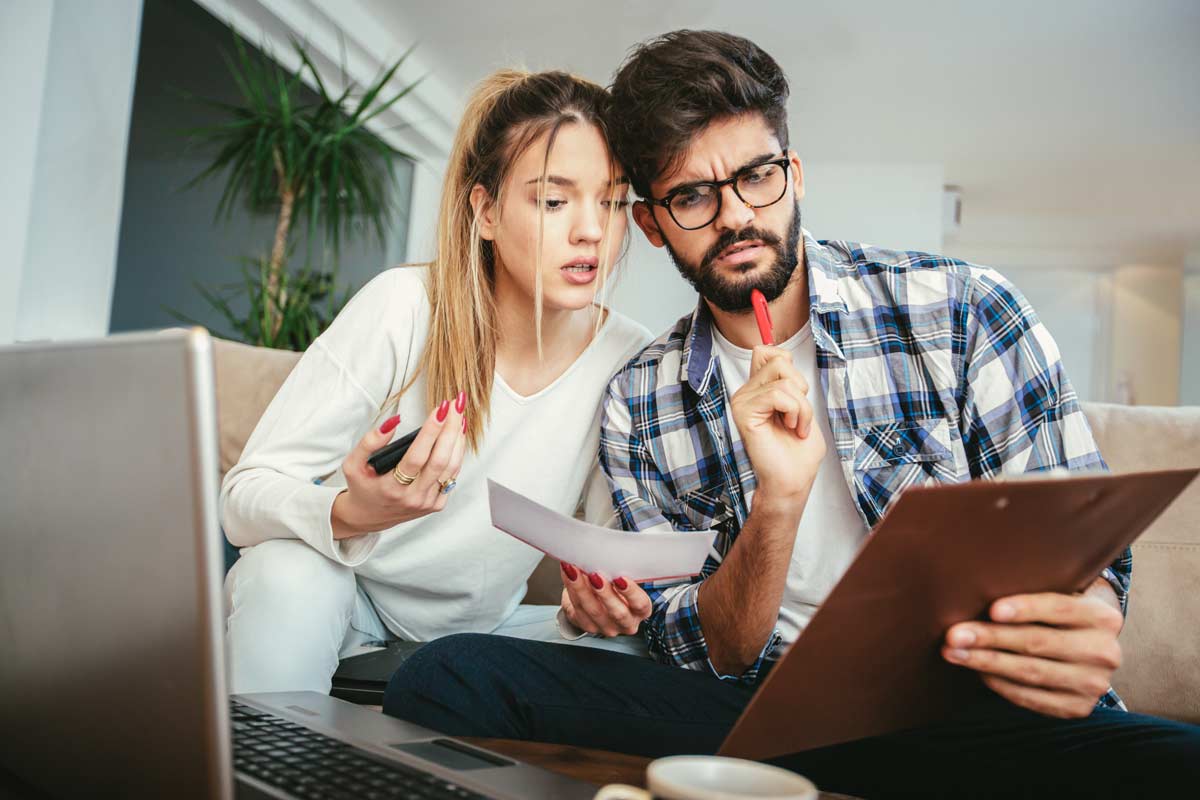 Confused couple looking at at bill and laptop