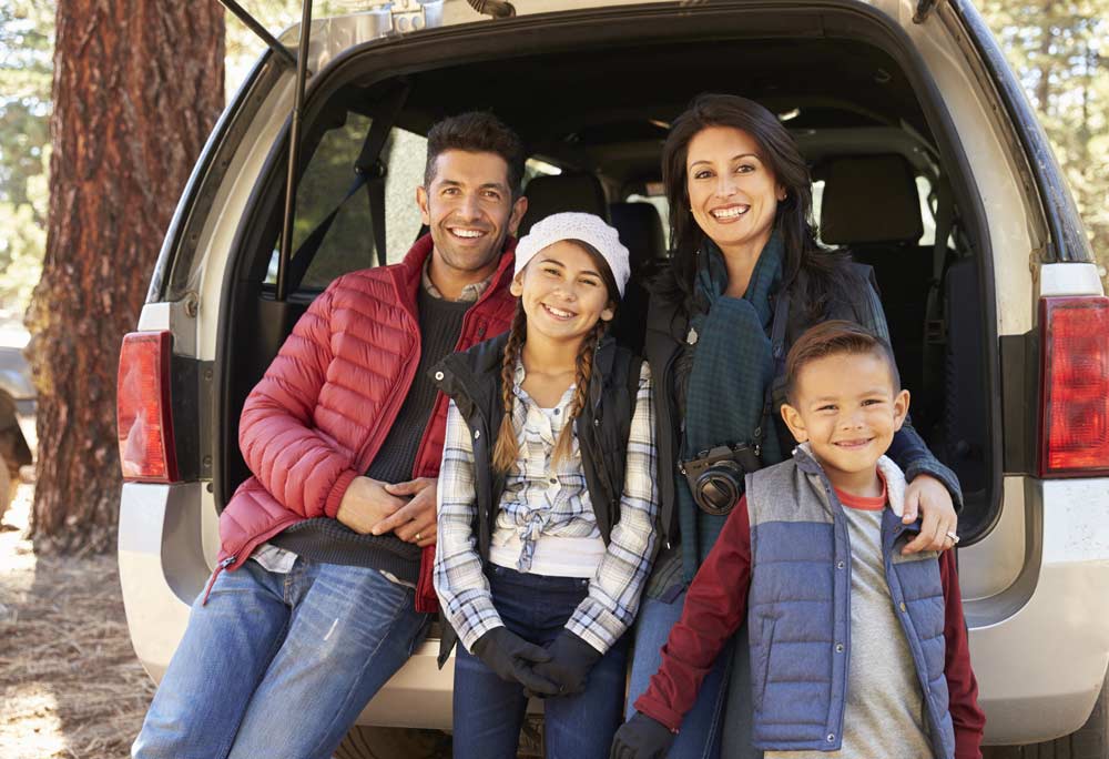 Family standing together behind SUV