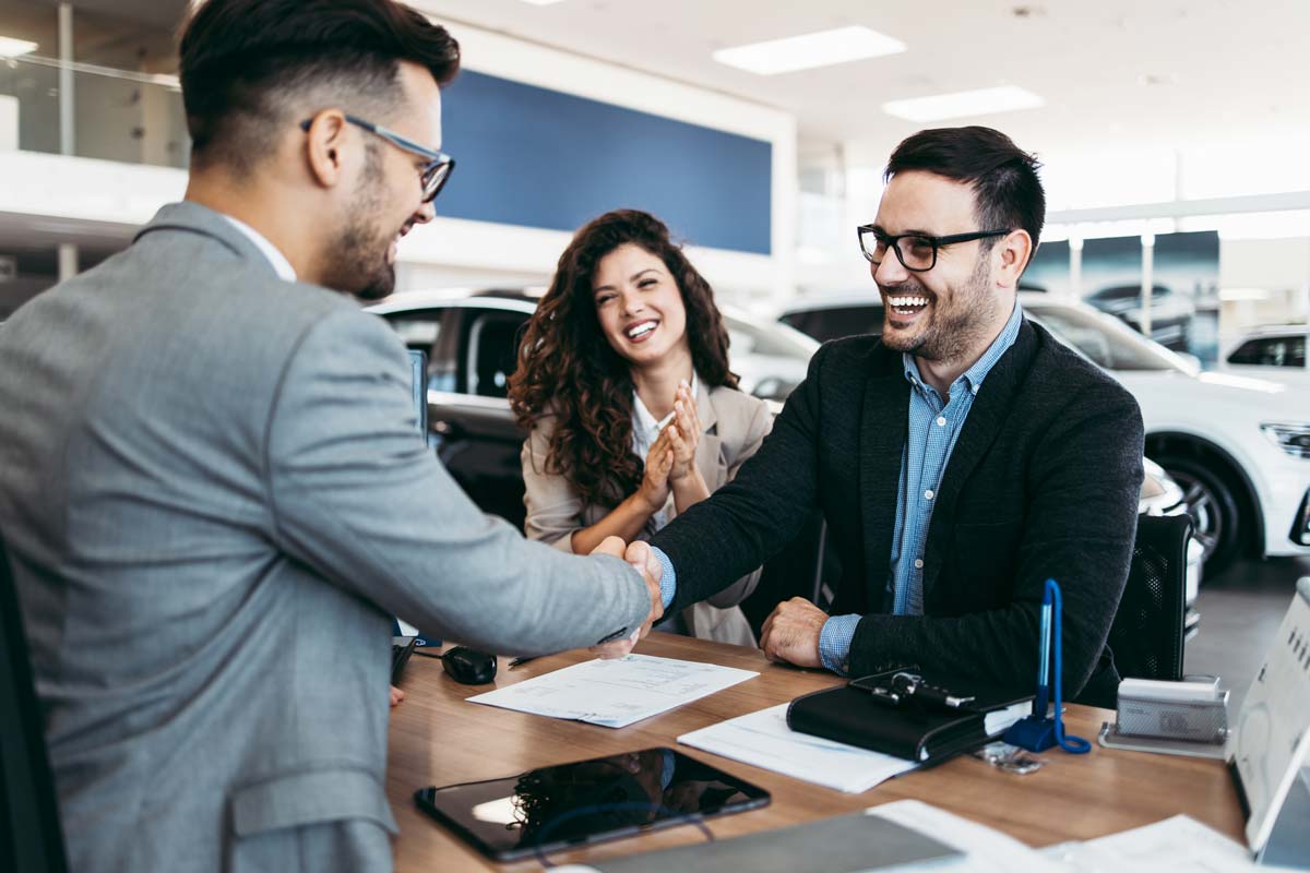 Man and salesman shaking hands over car purchase, having found the best way to finance the car.