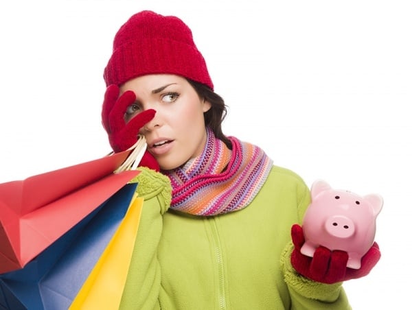 Concerned woman holding piggy bank and shopping bags