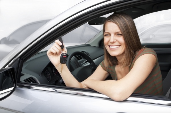 Young woman in car holding control and key