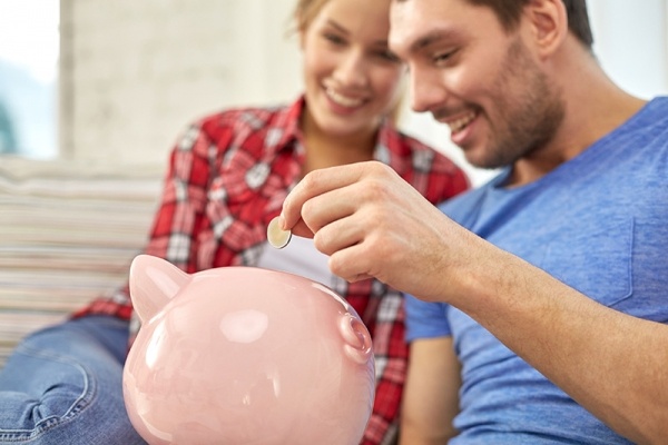 Couple putting money inside piggy bank